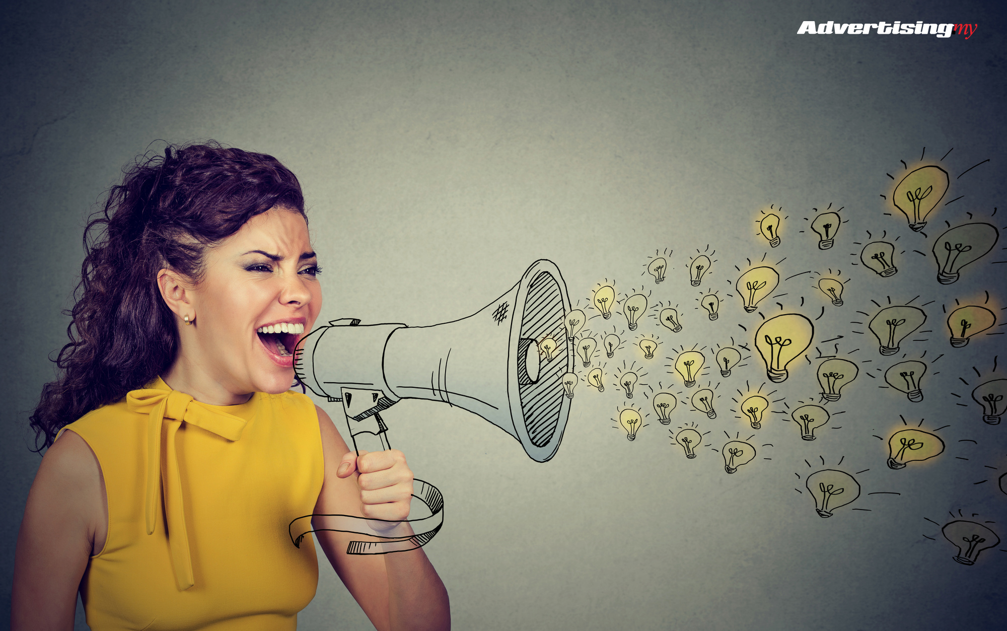 Business woman screaming out her ideas loud in megaphone isolated on gray wall background